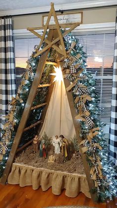 a nativity scene in the corner of a living room with christmas trees and plaid curtains