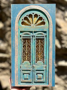 a hand holding up a small blue door