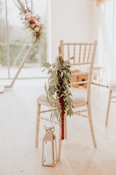 a chair with a plant on it and a lantern in front of the chair is decorated with greenery