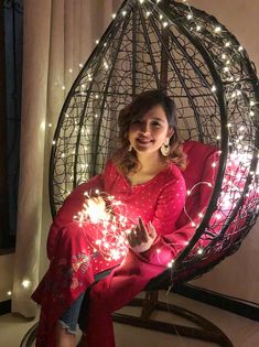 a woman sitting in a hanging chair holding sparklers