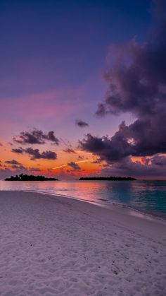 the sun is setting on an empty beach