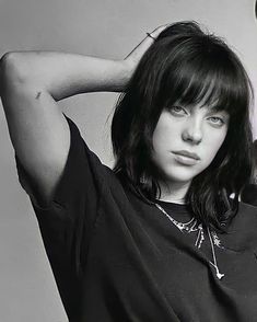 a black and white photo of a woman with her hand on her head wearing a t - shirt