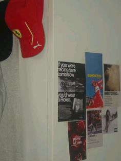 there is a red hat hanging on the wall next to some pictures and posters in this room