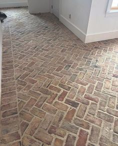 a brick floor in an empty room with a cat on the ground looking at it