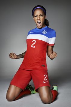 a female soccer player with her mouth open and hands in the air while posing for a photo