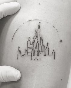 a person holding their arm with a castle tattoo on it's left side shoulder