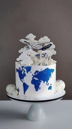 a blue and white cake with an airplane on top that is shaped like the world