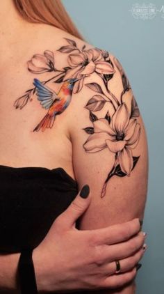 a woman's shoulder with flowers and a bird on it