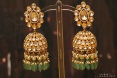 gold and green earrings on display in a store window, with beads hanging from them