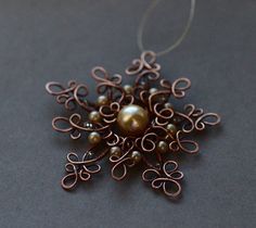 a metal snowflake ornament with pearls and filigrees