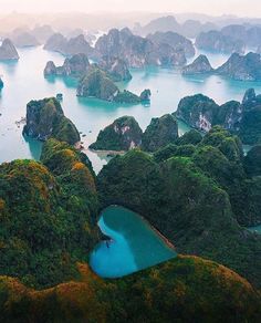 an aerial view of many small islands in the water and surrounded by green hills, rocks and trees