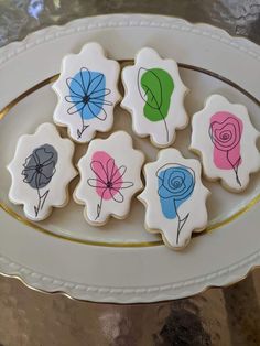 decorated cookies on a white plate with blue, pink, and green flowers in the middle