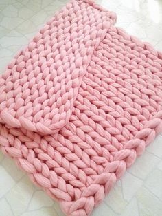 two pink knitted blankets sitting on top of a white tiled floor next to each other