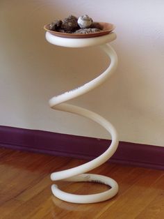 a white sculpture sitting on top of a hard wood floor next to a purple wall