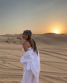 a woman standing in the desert at sunset