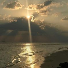 the sun is shining through clouds over the ocean