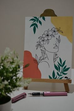 an easel with a drawing of a woman's face and flowers on it