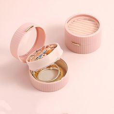 an open pink box with jewelry inside on a white surface