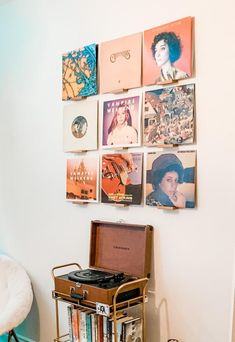 a record player sitting on top of a metal cart in front of a wall covered with records