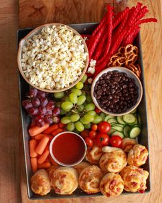 a tray filled with grapes, carrots, crackers and other foods next to some dipping sauce