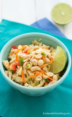 a blue bowl filled with rice and veggies next to a lime slice on top