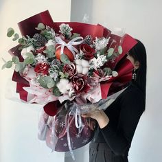 a woman holding a large bouquet of flowers in her right hand and wearing a black sweater