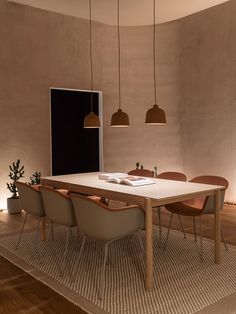 a dining table with four chairs and a book on it in front of a window