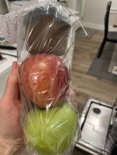 a person holding two apples wrapped in plastic