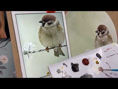 two birds sitting on top of a piece of paper next to paintbrushes and an artist's palette