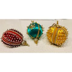 three pieces of jewelry sitting on top of a white table next to each other in different colors