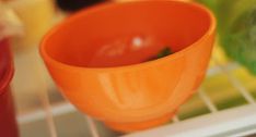 an orange bowl sitting on top of a refrigerator