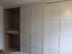 an empty bedroom with white closet doors and drawers on the wall, next to a bed