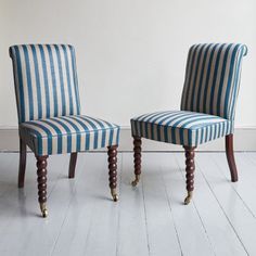 two blue and white striped chairs sitting next to each other on top of a hard wood floor