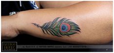 a close up of a person's arm with a peacock feather tattoo on it