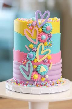 a multi - colored cake decorated with flowers and hearts