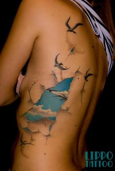 a woman's back with birds flying in the sky on her side and behind her