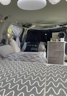 the interior of a camper van with pillows and blankets on it's bed