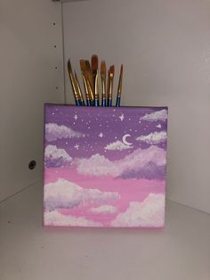 there are brushes in the holder that is on top of the shelf next to the paintbrushes