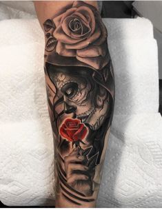 a tattoo with a skull and rose on the leg, in black and grey colors