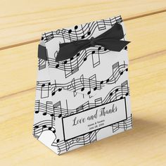 a music note gift bag with a black bow on the front and white notes on the back