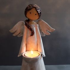 an angel figurine holding a lit candle