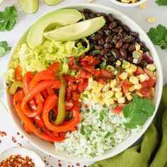 a white bowl filled with rice, beans, corn and avocado on top of a table