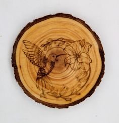 a wooden plaque with a bird and flowers on it's side in the shape of a circle