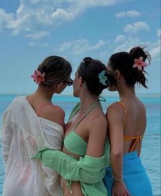 three women standing next to each other near the ocean