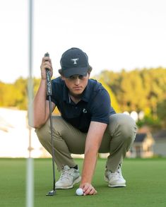 a man kneeling down to put his golf ball on the green