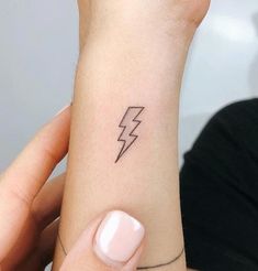 a woman's arm with a lightning tattoo on the left side of her wrist