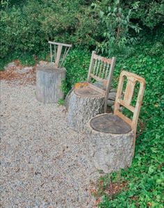 two wooden chairs sitting next to each other on top of a gravel road covered ground