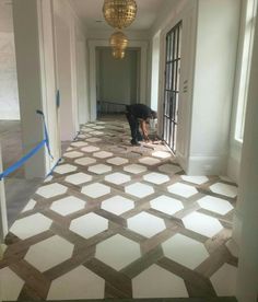 a person kneeling down on the floor in an empty room with white and brown tiles