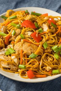 a white bowl filled with noodles and chicken on top of a blue napkin next to a fork