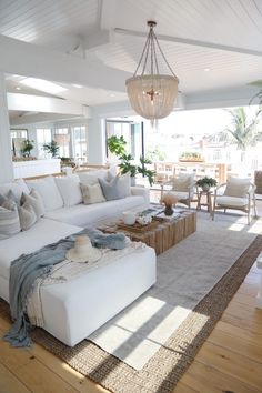 a living room filled with furniture and a chandelier hanging over the top of it